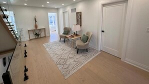 A spacious living area with a staircase, a dining table, two chairs, and a decorative vase. - Lakeside Gem - Frenchman's Bay (Pickering)