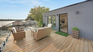 A modern outdoor deck with wicker furniture and a glass door leading to an interior space. - Lakeside Gem - Frenchman's Bay (Pickering)