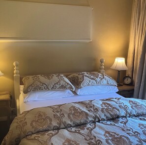A neatly made bed with patterned bedding, a bedside lamp, and a clock on the nightstand. - Foxglove Luxury accommodation stay. Tranquil retreat in Tilba Tilba (Tilba Tilba)