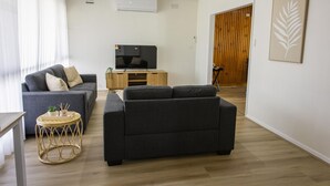 A modern living room with two sofas, a TV, and a wooden cabinet.