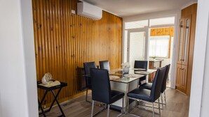 A dining area with a wooden wall, a glass table, and black chairs.
