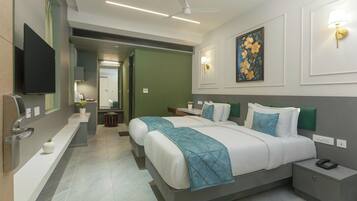 A modern hotel room with two beds, a flat-screen TV, a desk, and a bathroom visible through an open door.