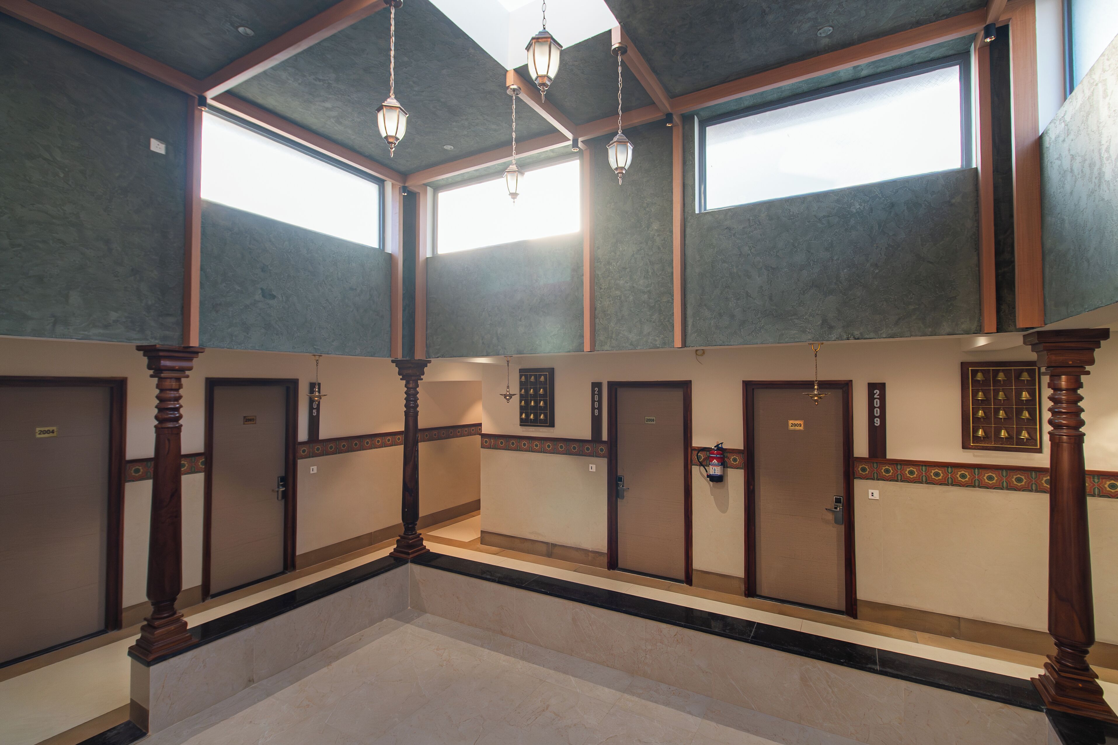 A hotel lobby with multiple doors, a marble floor, and hanging light fixtures.