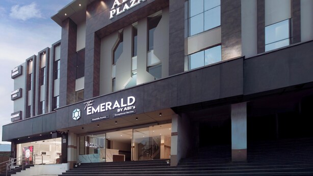 A modern building with a sign for 'ABI'S PLAZA' and 'The Emerald by ABI'S Exceptional Service'. - The Emerald (Thanjavur)