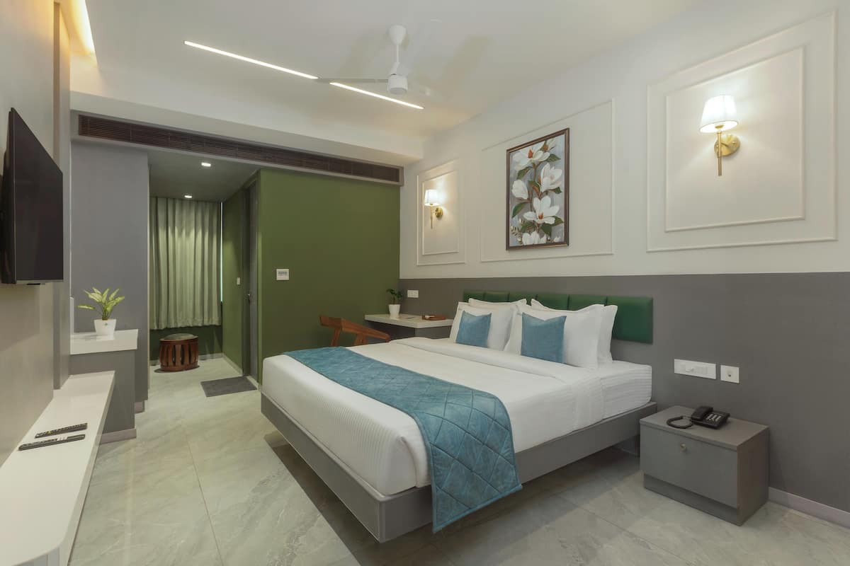 A modern hotel room with a large bed, bedside tables, a desk, and a chair.