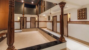 A spacious lobby with a marble floor, wooden columns, and a mezzanine level with a staircase. - The Emerald (Thanjavur)