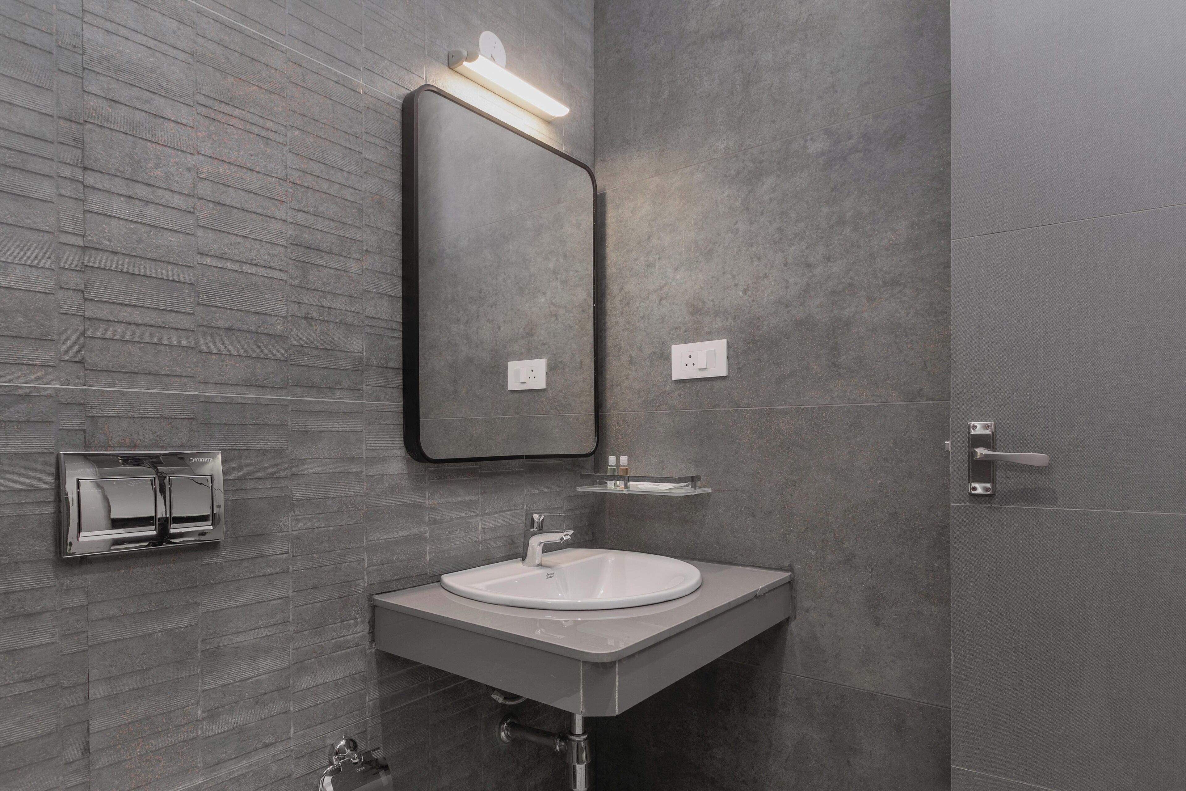 A modern bathroom with a rectangular mirror, a white sink, and a wall-mounted towel rack.