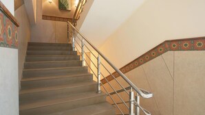 A staircase with a metal handrail and patterned wall trim. - The Emerald (Thanjavur)