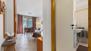 Une chambre d’hôtel comprenant un lit, un bureau, une chaise, une fenêtre avec des rideaux, une salle de bain avec un lavabo et une porte.