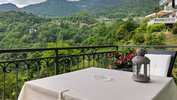 Un balcon avec une table, une lanterne et une vue sur un paysage montagneux.