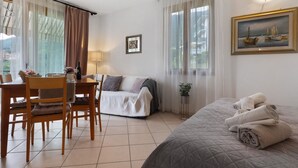 Une chambre d’hôtel avec un lit, une table à manger avec des chaises, un canapé et un tableau au mur.