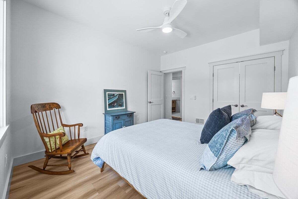 Un dormitorio con cama, una mecedora, un escritorio y un ventilador de techo.