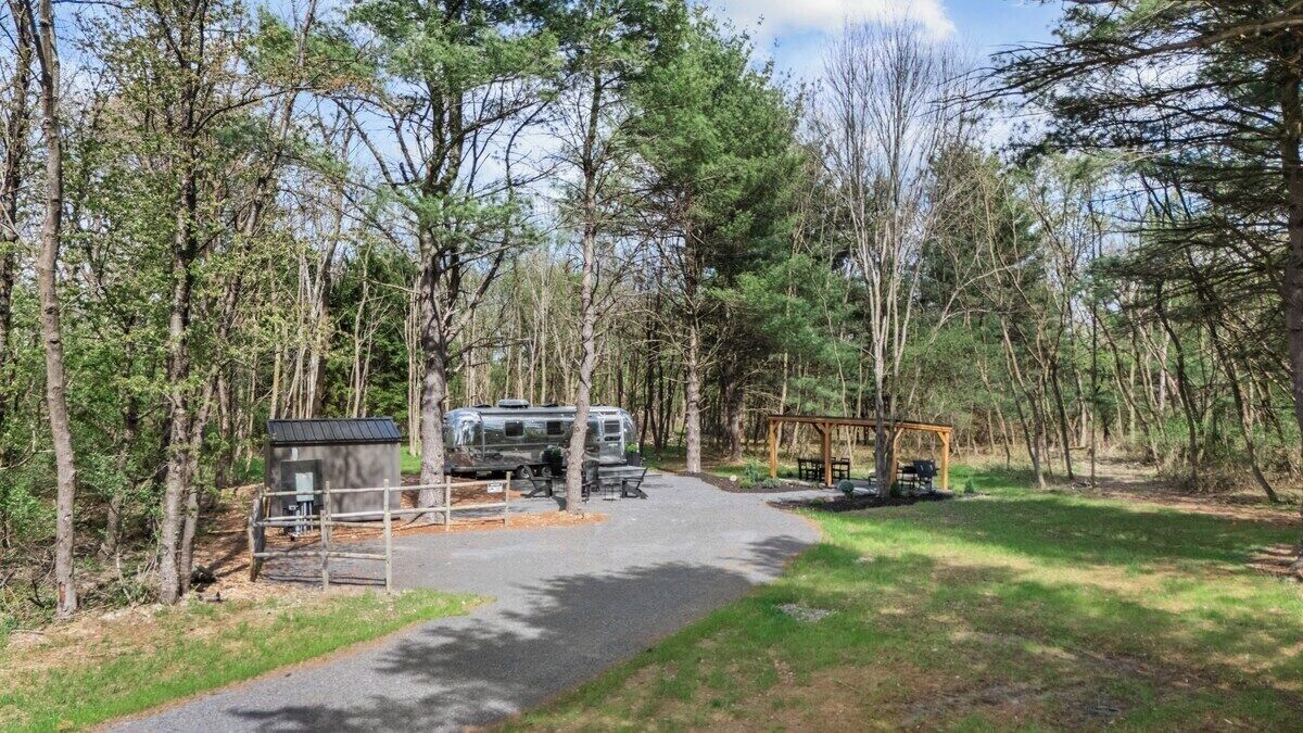 Un campament amb aparcament per vehicles recreatius, taules de pícnic i una petita cabana.