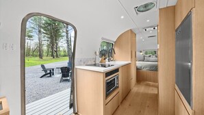 Una cocina compacta con horno integrado, un lavamanos y un pequeño comedor con sillas.