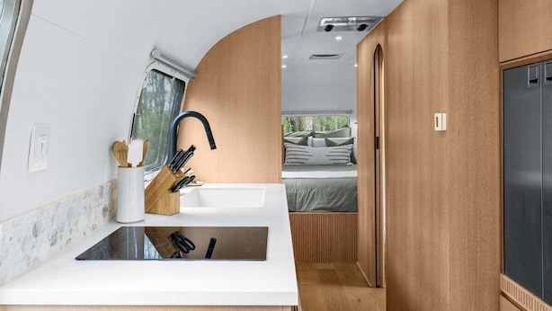 Cocina compacta para autocaravana con encimera blanca, un lavabo y una ventana.