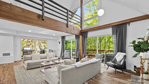 A spacious living room with a high ceiling, large windows, and a view of the outdoors. - Dog-Friendly Pocono Chalet w/ Hot Tub, Indoor Pool (Long Pond)