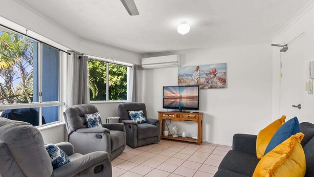 Una sala de estar con sofá, sillones, televisor y un cuadro.