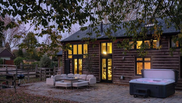 A wooden house with a patio area featuring outdoor furniture and a hot tub. - Campden Barn - Luxury Home with Hot Tub (Chipping Campden)