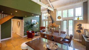 A spacious kitchen with a large island, a dining area with a table and chairs, and a staircase leading to another level. - Campden Barn - Luxury Home with Hot Tub (Chipping Campden)