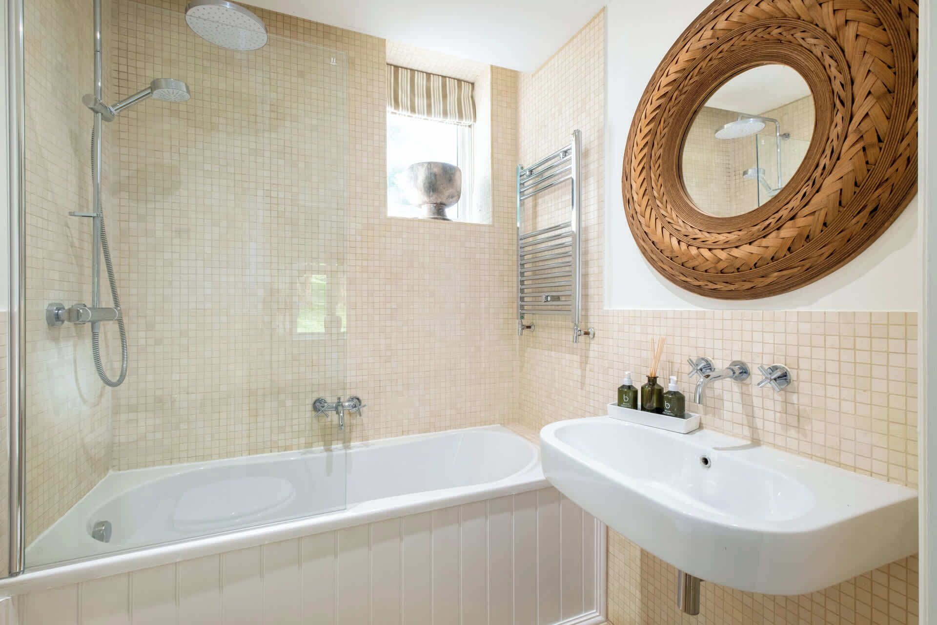 Une salle de bain dotée d’une douche à parois de verre, d’une baignoire sur pieds et d’un lavabo blanc avec un miroir au-dessus.