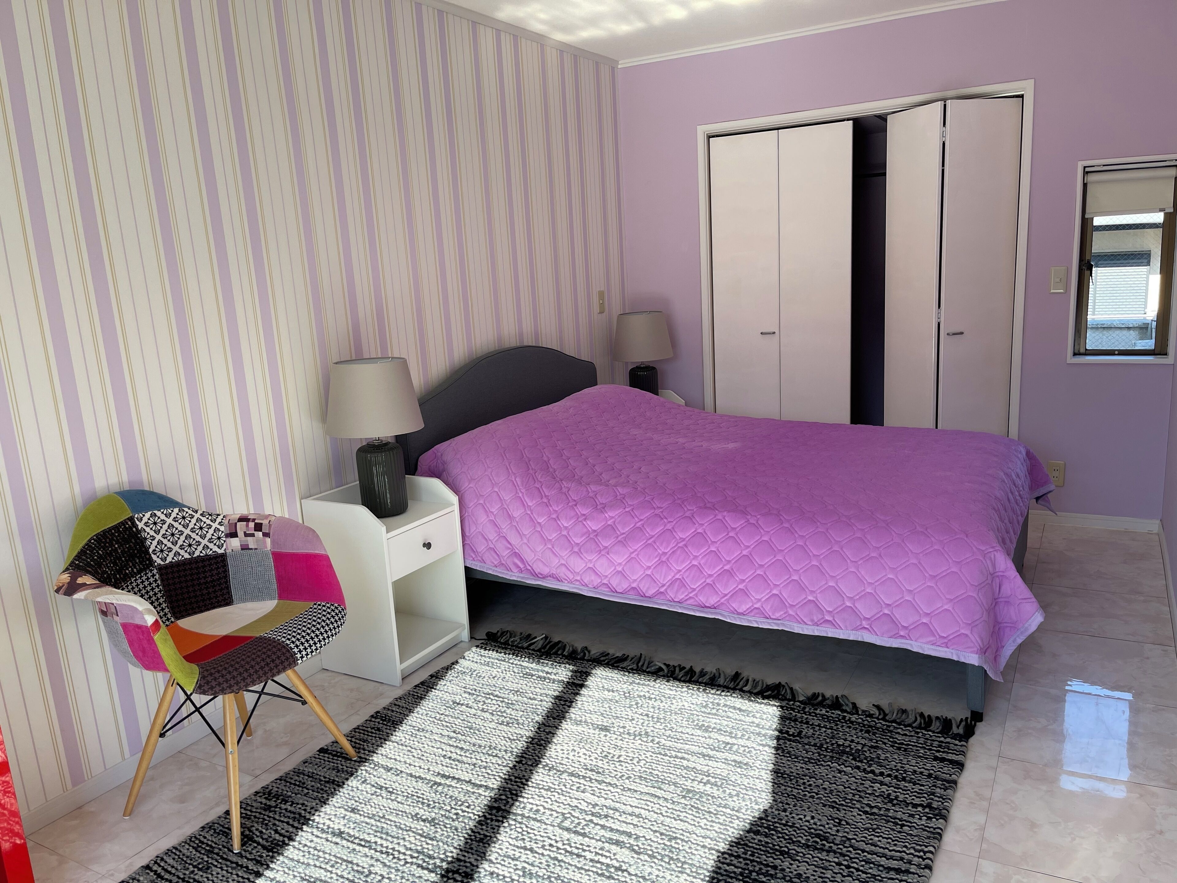 A bedroom with a bed, bedside tables, a chair, and a wardrobe.