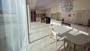 A modern kitchen with white cabinets, a dining table with chairs, and a large decorative light fixture. - Quiet residence near to shibuya (2f) (世田谷区)