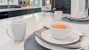 A modern kitchen with white appliances, a large island, and a dining area with white tableware. - Beautiful 3 Bedroom Retreat walking distance to Downtown St. Michaels (Saint Michaels)