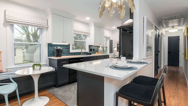 A modern kitchen with white cabinetry, a central island, and a dining area with two chairs. - Beautiful 3 Bedroom Retreat walking distance to Downtown St. Michaels (Saint Michaels)