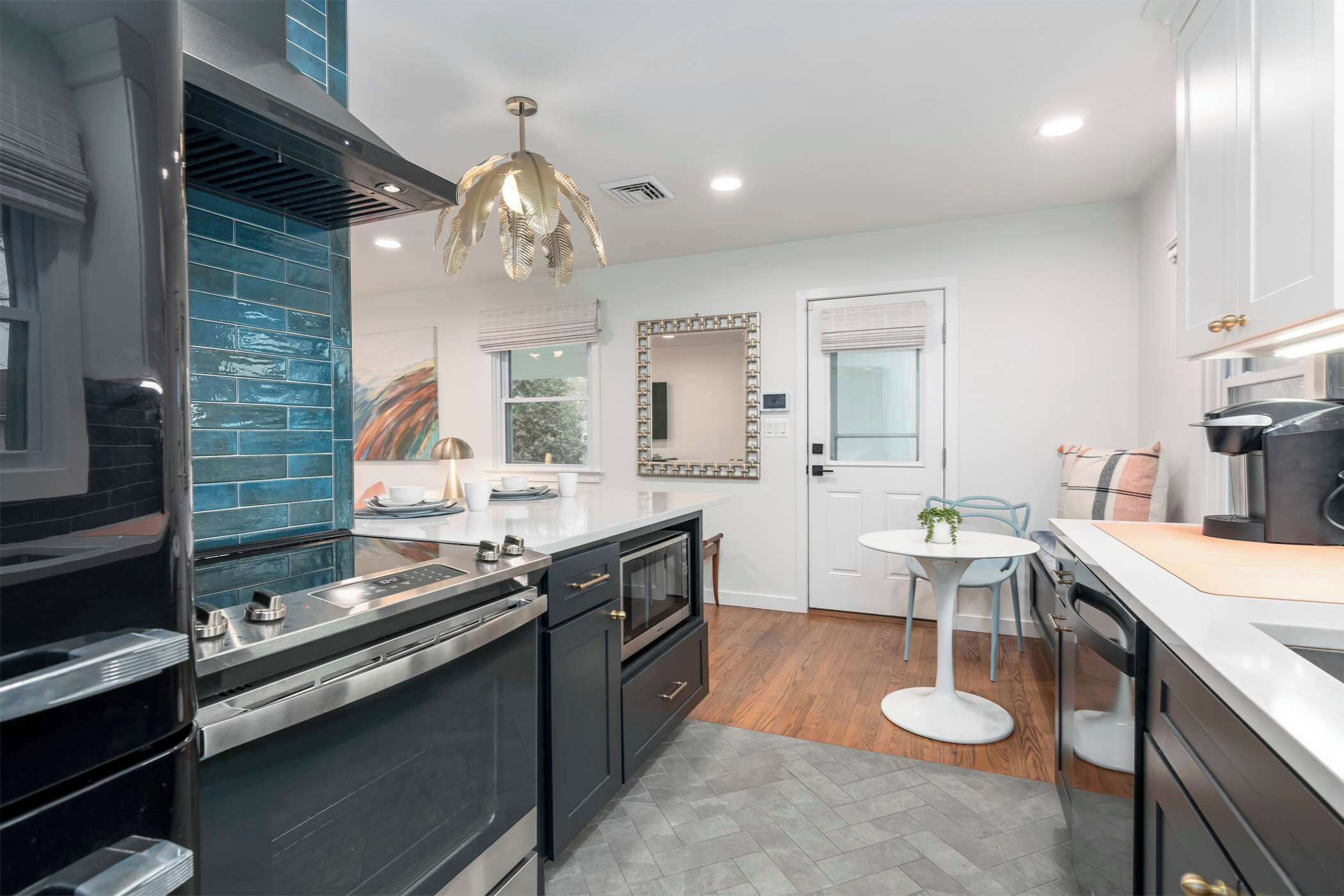 Une cuisine moderne avec des meubles de couleur sombre, un îlot central et un luminaire suspendu.