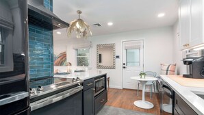A modern kitchen with dark cabinetry, a central island, and a pendant light. - Beautiful 3 Bedroom Retreat walking distance to Downtown St. Michaels (Saint Michaels)