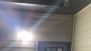 Une porte sur laquelle est inscrit le numéro « 203 », une fenêtre à carreaux et un plafond avec des poutres apparentes.