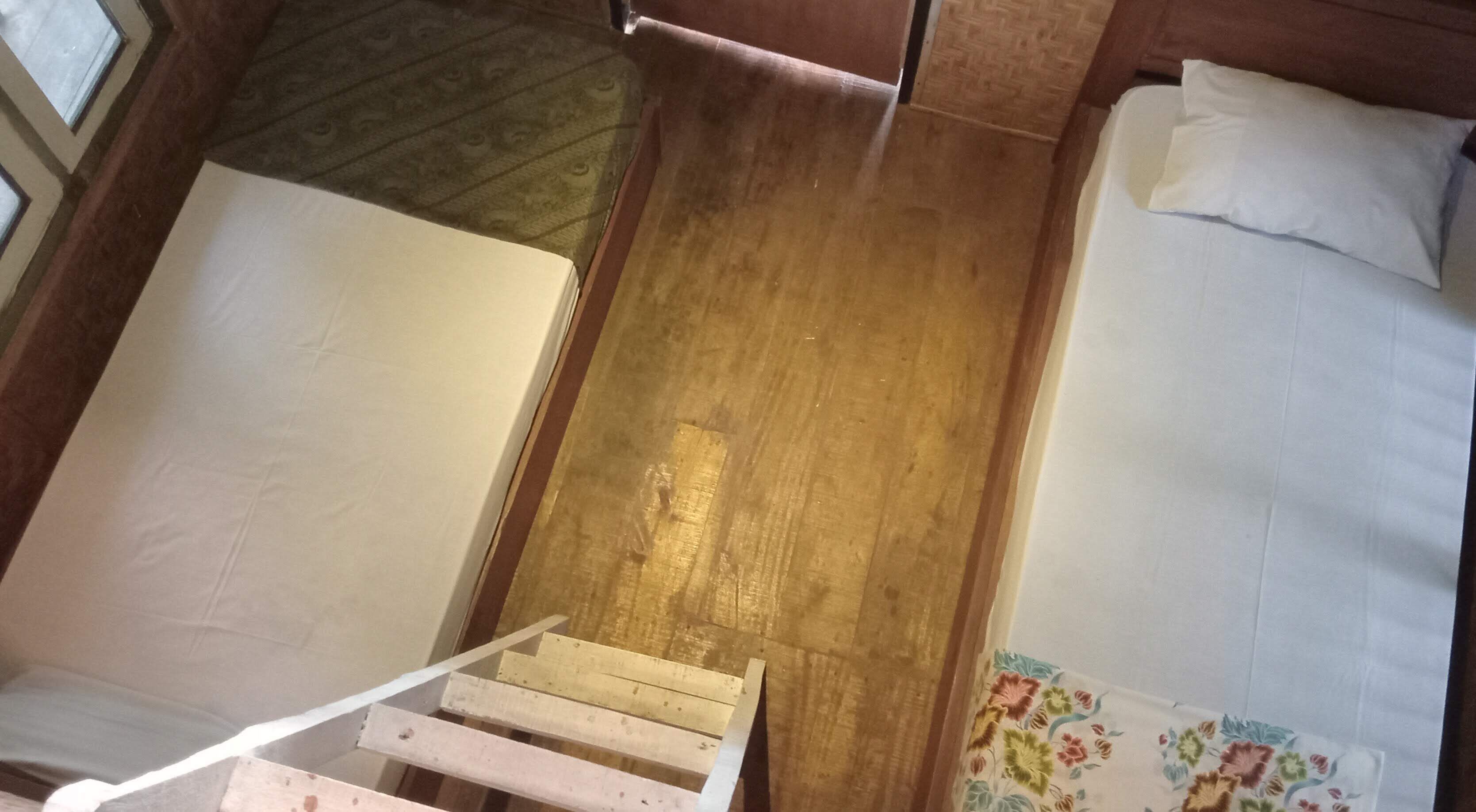 Een smalle, houten trap die leidt naar een bed met wit beddengoed.