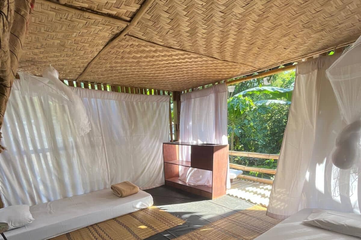 A room with two beds, a small table, and a bench.