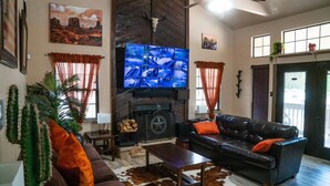 Uma sala de estar com lareira, televisão na parede e sofá de couro.