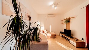A modern living room with a sofa, a TV, and a plant.