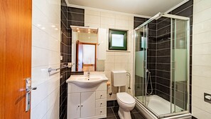 A bathroom with a glass-enclosed shower, a sink, and a toilet.