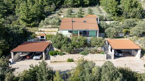 A two-story house with a tiled roof, a stone wall, and a garage with a parked car.