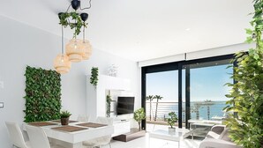 Una sala de estar moderna con comedor, ventanas amplias y vista al mar.