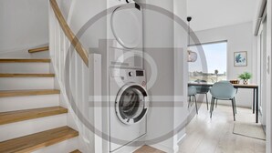 A modern apartment with a wooden staircase, a built-in washer and dryer, a dining area with a view, and a small table with chairs. - Havnehusene, Lejl. 59 (Slagelse)