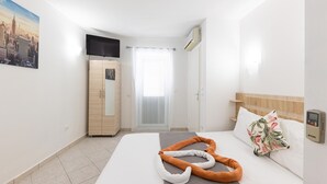 A hotel room with a bed, a TV, a wardrobe, and a window with blinds. - 1 bedroom nice apartment in Baska Voda (Baska Voda)