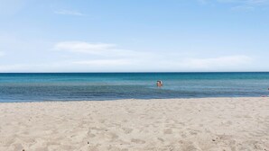 Une plage avec une eau d’un bleu limpide et un rivage sablonneux.