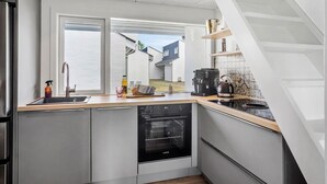 Une cuisine moderne équipée d’un lave-vaisselle encastré, d’une machine à café et d’une bouilloire posées sur le plan de travail.