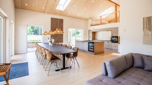 A spacious living area with a dining table, sofas, and a kitchen with modern appliances.