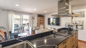 A modern kitchen with a black marble countertop, stainless steel sink, and wooden cabinets. There is a dining area with a table and chairs, and a balcony with a view. - Beautiful apartment in Santa Pola with WiFi (Santa Pola)