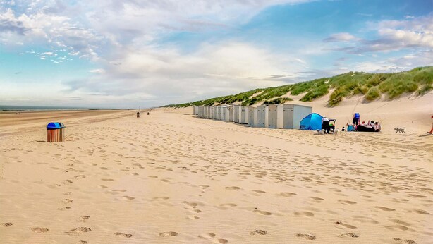 Une plage équipée de toilettes portables et d’une poubelle.