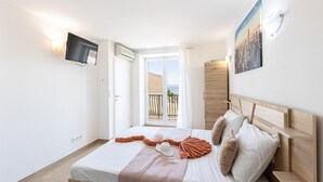 Une chambre avec un lit, une télévision, une armoire et un balcon offrant une vue sur la ville.