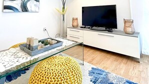 A modern living room with a glass coffee table, a yellow pouf, a flat-screen TV, and a white cabinet. - Nice home in Primorski Dolac (Primorski Dolac)