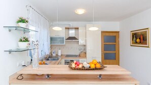 A modern kitchen with glass shelves, a fruit bowl, and a painting on the wall. - Nice home in Primorski Dolac (Primorski Dolac)