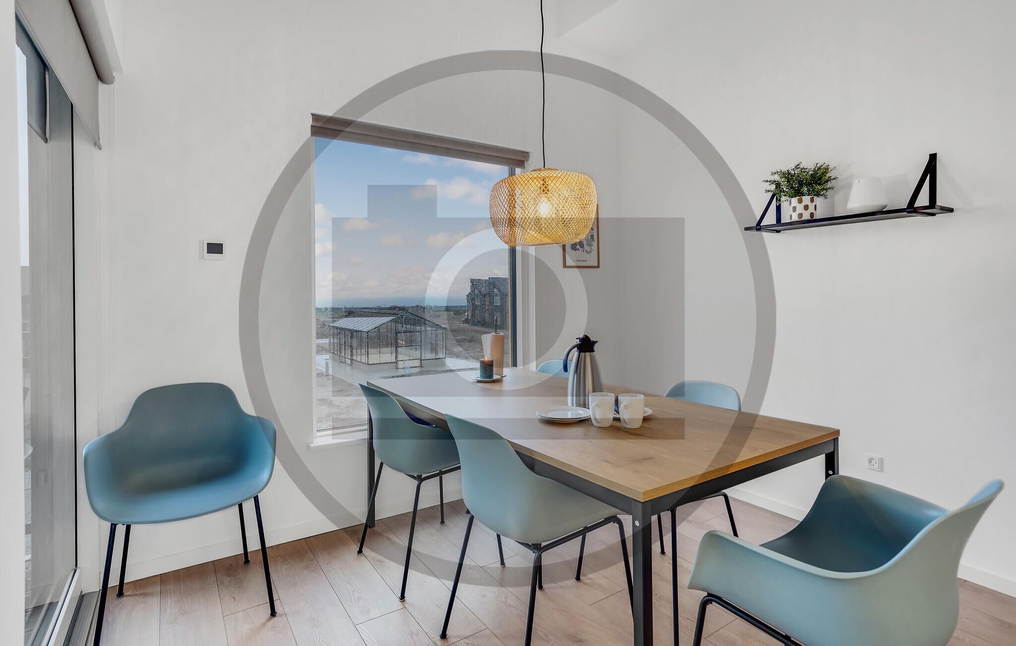 A modern dining area with a wooden table, four blue chairs, a hanging light fixture, and a view of a cityscape through a large window.
