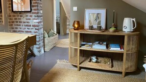 A cozy loft bedroom with exposed brick walls, a sloped ceiling, and a wooden console table with books and decorative items. - Double room with private bathroom (Senlis)